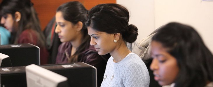 A group of female students working on the computers in the library common areas.